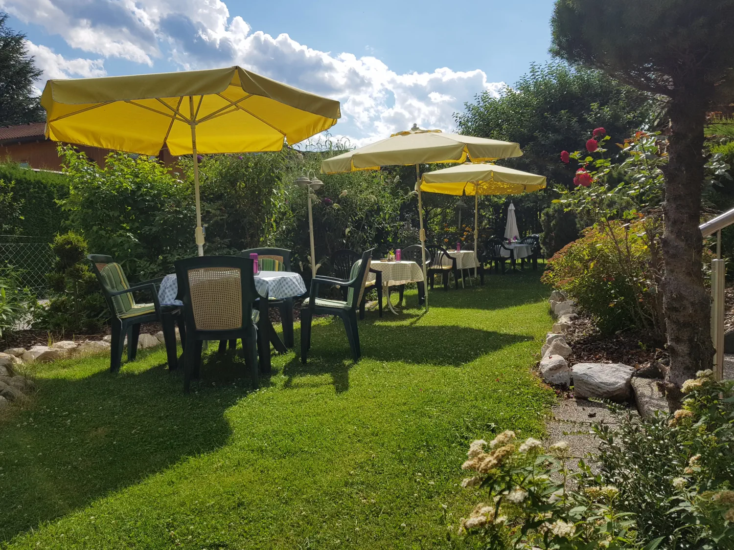 Die gemütliche Gartenterrasse mit Sonnenschirmen an einem warmen Sommertag