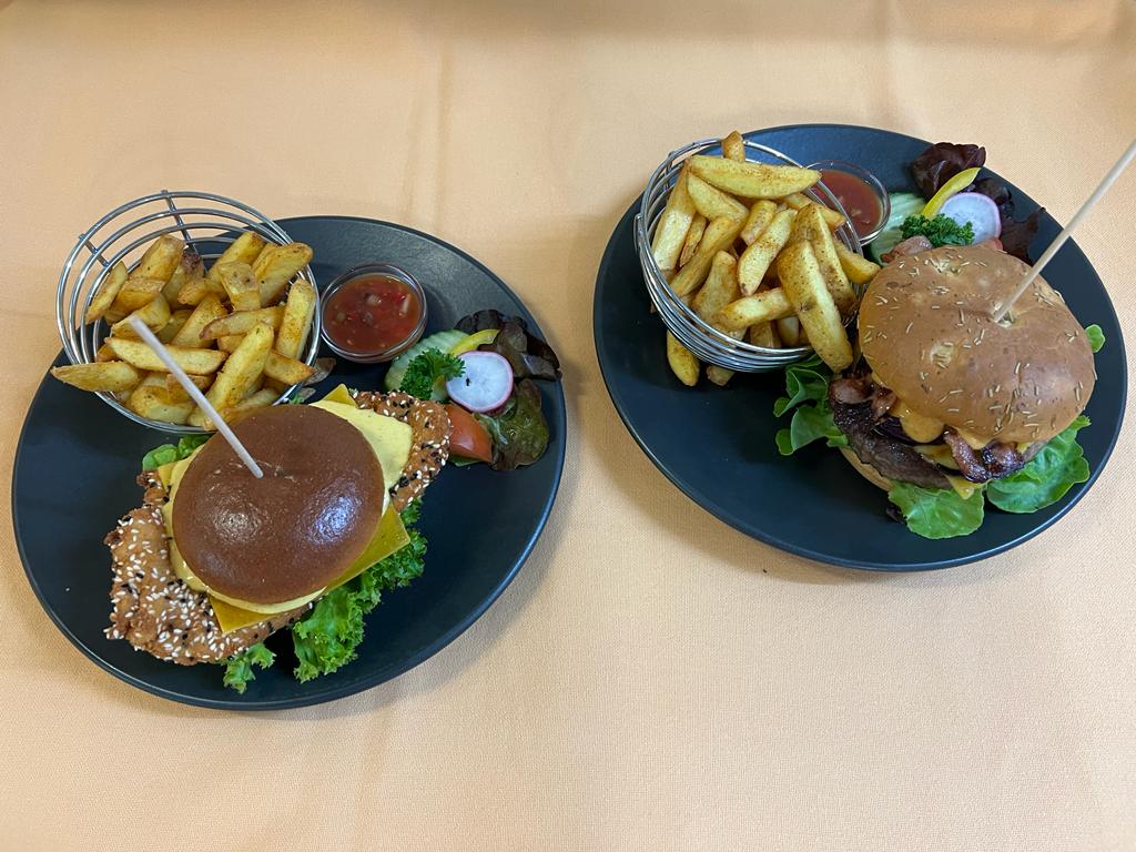 Burger-Variationen mit hausgemachten Pommes auf schwarzen Tellern serviert