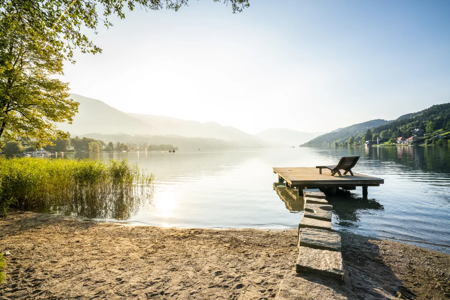 Abendstimmung. Ein Steg mit einer Liege darauf auf einem Steg der in der in den Millstätter See ragt