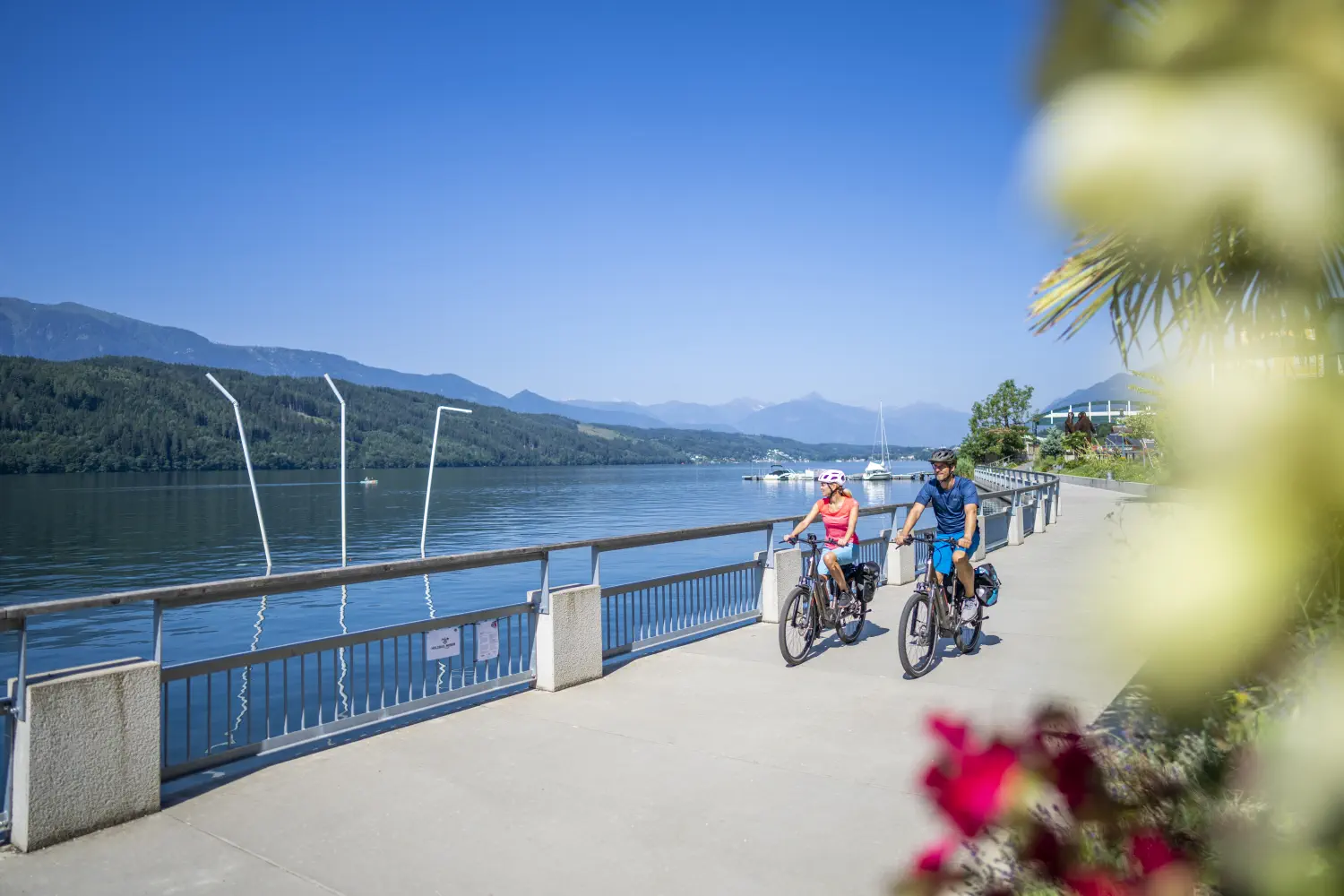 Zwei Radfahrer fahren auf der Seepromenade entlang des Millstätter Sees